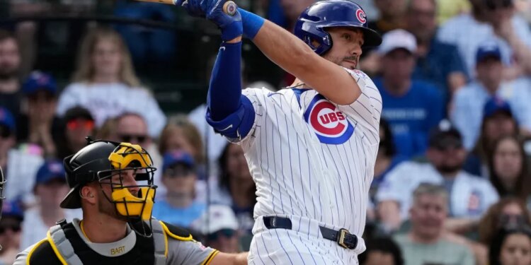 Michael Conforto in a white Cubs uniform with blue pinstripes hitting a baseball.