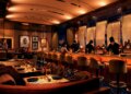 Illustration of a restaurant interior with a bar, chefs, and dining tables.