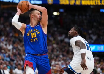 Nikola Jokic with the ball above his head, guarded by Naz Reid.
