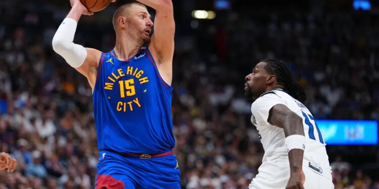 Nikola Jokic with the ball above his head, guarded by Naz Reid.