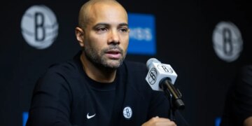 Jordi Fernandez speaking at a press conference with a microphone in front of him.