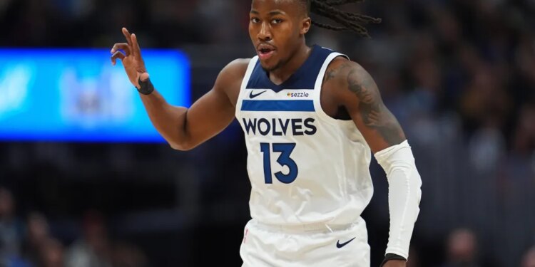 Ayo Dosunmu in a white "Wolves 13" jersey with his right arm raised and dreadlocks flowing to the right.