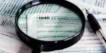 A magnifying glass and pen over a 2025 US Individual Income Tax Form 1040.