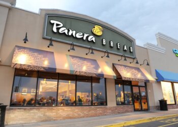 Exterior of a Panera Bread restaurant with its sign and awnings, next to a Carter's store.
