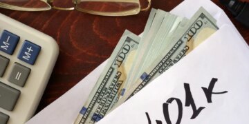 An envelope with "401k" written on it, filled with US dollar bills, next to a calculator and eyeglasses.