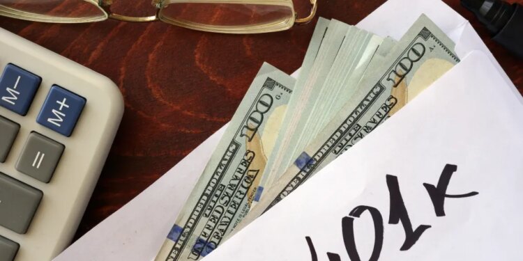 An envelope with "401k" written on it, filled with US dollar bills, next to a calculator and eyeglasses.