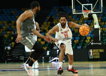 J. Cole dribbling the ball against another player during a basketball game.