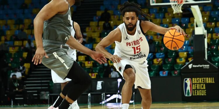 J. Cole dribbling the ball against another player during a basketball game.
