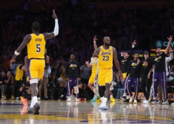 LeBron James (23) of the Los Angeles Lakers celebrates after a play with another Lakers player (5), as other Lakers players and fans cheer.