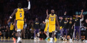 LeBron James (23) of the Los Angeles Lakers celebrates after a play with another Lakers player (5), as other Lakers players and fans cheer.