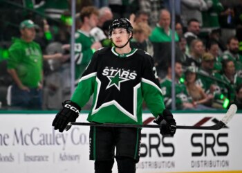 Dallas Stars left wing Jason Robertson in black and green uniform with his hockey stick.