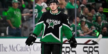 Dallas Stars left wing Jason Robertson in black and green uniform with his hockey stick.