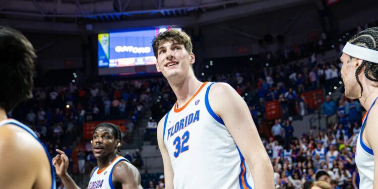 Olivier Rioux in a Florida Gators basketball uniform smiling on the court with teammates.