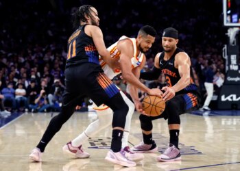 Atlanta Hawks guard CJ McCollum losing the ball to New York Knicks guards Jalen Brunson and Josh Hart during a basketball game.