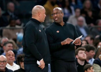 New York Knicks assistant coach Rick Brunson talks with head coach Mike Brown during an NBA game.