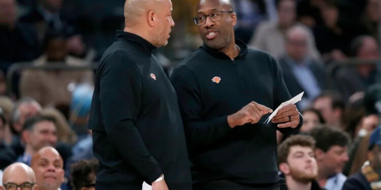 New York Knicks assistant coach Rick Brunson talks with head coach Mike Brown during an NBA game.