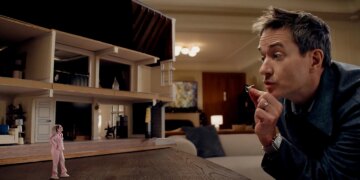 A tiny woman standing next to a bisected dollhouse as she has an argument with a gigantic man the size of a mountain.