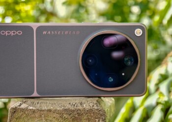 Photo of Oppo Find X9 Ultra resting horizontally on a wooden post in front of green plants, showing the rear cameras