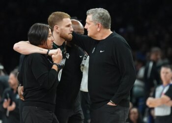 Donte DiVincenzo being helped off the court by medical staff and acknowledged by coach Chris Finch.