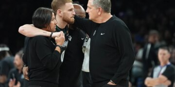 Donte DiVincenzo being helped off the court by medical staff and acknowledged by coach Chris Finch.