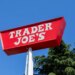 Red Trader Joe's sign against a blue sky, with pine trees visible.