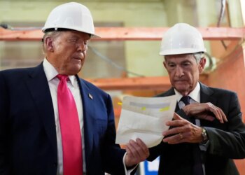 President Donald Trump and Federal Reserve Chairman Jerome Powell wearing hard hats and looking at a document.