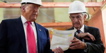 President Donald Trump and Federal Reserve Chairman Jerome Powell wearing hard hats and looking at a document.