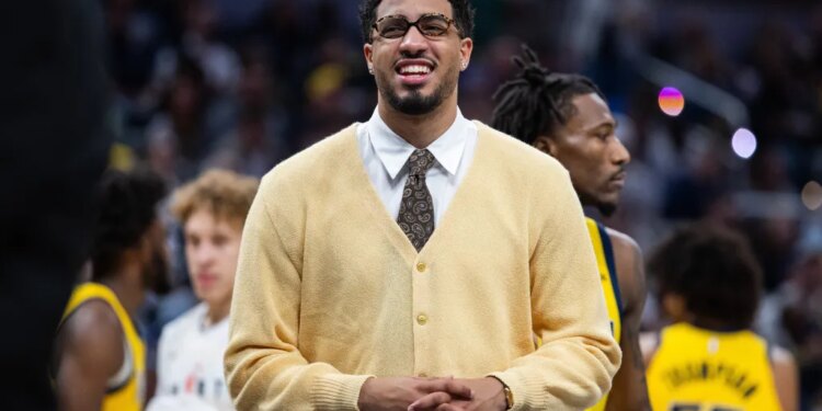 Indiana Pacers guard Tyrese Haliburton smiling while wearing a yellow cardigan, white collared shirt, and patterned tie.