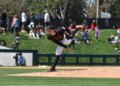 A baseball pitcher in a black and orange uniform mid-delivery.