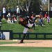 A baseball pitcher in a black and orange uniform mid-delivery.