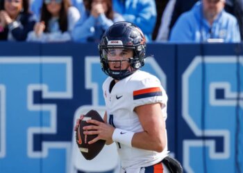 Chandler Morris wearing a white Virginia football jersey and black helmet, holding a football.