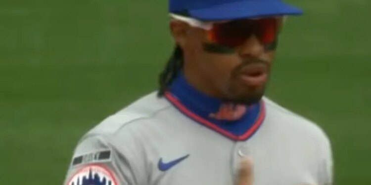 Baseball player in a New York Mets uniform with sunglasses and a hat with the team's logo.