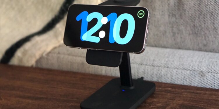 A photo of an iPhone in StandBy mode on a wood desk.