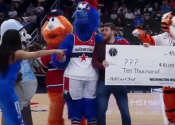A fan posing for a photo with the Washington Wizards mascots and a fake check for $10,000 for an April Fool's Day prank.