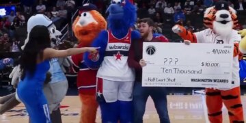 A fan posing for a photo with the Washington Wizards mascots and a fake check for $10,000 for an April Fool's Day prank.