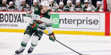 Quinn Hughes of the Minnesota Wild skates with the puck during a hockey game.