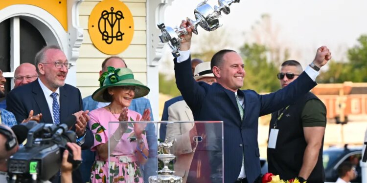 Chad C. Brown, trainer of horse Early Voting, holds the Woodland Vase after his horse won the 147th running of the Preakness Stakes.