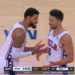 Two basketball players in white jerseys with red and blue accents, facing each other on the court.