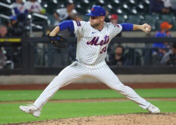 New York Mets pitcher throwing a baseball during a game against the Cincinnati Reds.