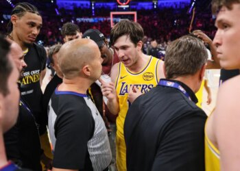 Austin Reaves talking with referee John Goble after a basketball game.