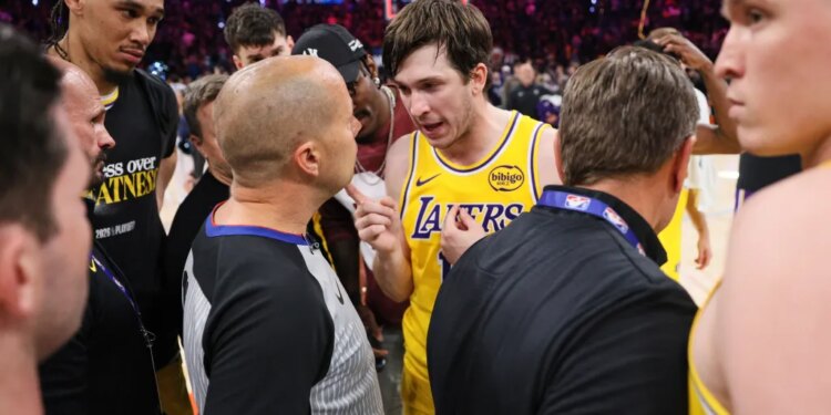 Austin Reaves talking with referee John Goble after a basketball game.