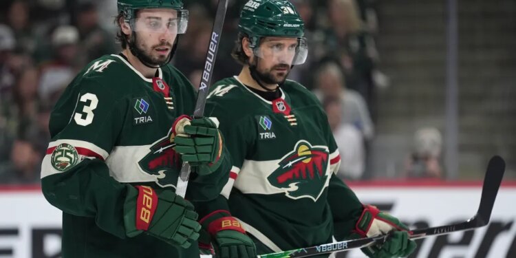 Minnesota Wild players Quinn Hughes and Ryan Hartman on the ice during an NHL playoff game.