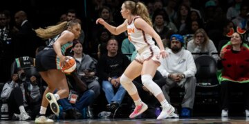 Betnijah Laney-Hamilton dribbles the basketball while being guarded by Gianna Kneepkens during a game.