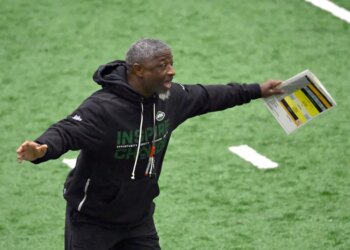 Jets head coach Aaron Glenn shouting and holding papers during practice.