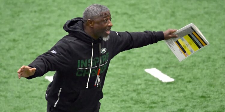 Jets head coach Aaron Glenn shouting and holding papers during practice.