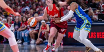 Caitlin Clark (22) reacting to contact from Arike Ogunbowale (24) during a WNBA game.