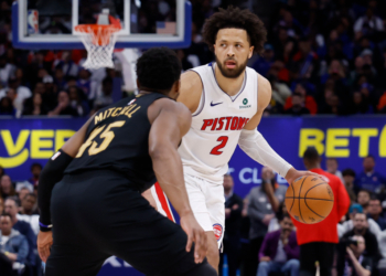 Detroit Pistons guard Cade Cunningham dribbles past Cleveland Cavaliers guard Donovan Mitchell during a game.