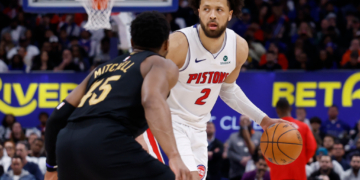 Detroit Pistons guard Cade Cunningham dribbles past Cleveland Cavaliers guard Donovan Mitchell during a game.