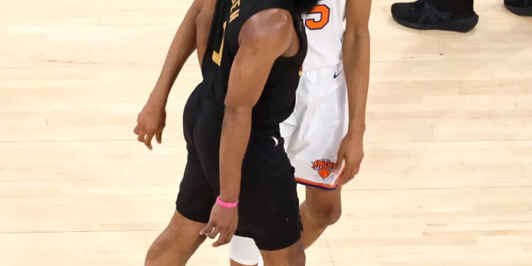 Two basketball players, one in a black jersey and one in a white jersey, standing on a court.