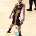 Two basketball players, one in a black jersey and one in a white jersey, standing on a court.